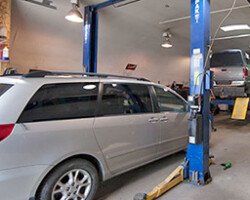 Minivan parked at a two-post lift in service bay